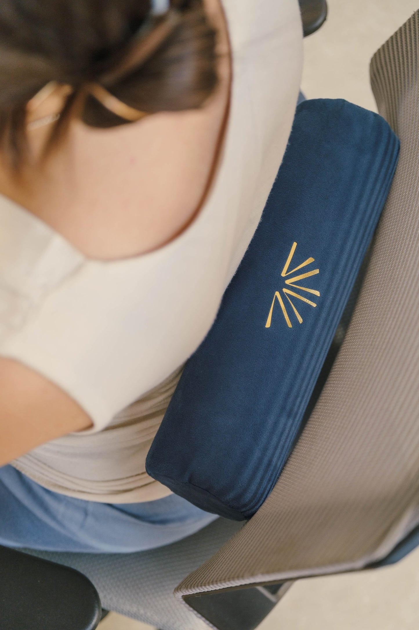 Person using blue Axis Roll as lumbar support while sitting in office chair.